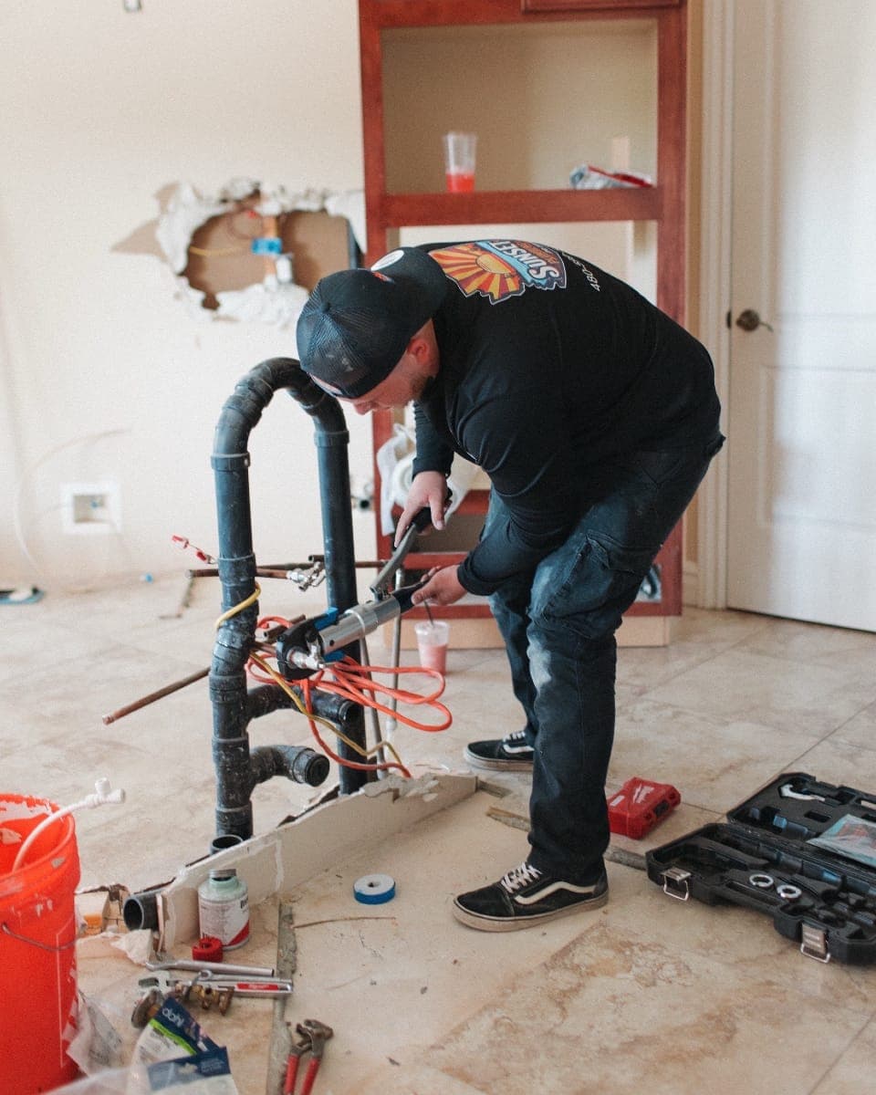 Sunset Home Services technician working on rough-in plumbing inside a Gilbert home